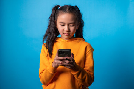 the studio isolated a portrait of the girl using smartphone and blue backdropの写真素材