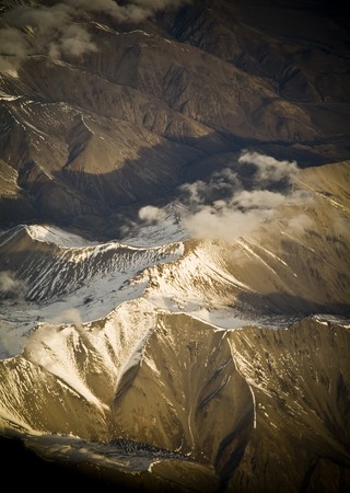 Aerial view of mountain range with snow capped peaks in late afternoon lightの写真素材