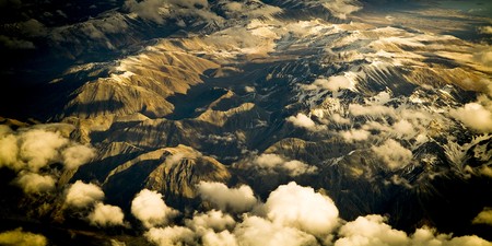 Aerial view of mountain range with snow capped peaks in late afternoon light