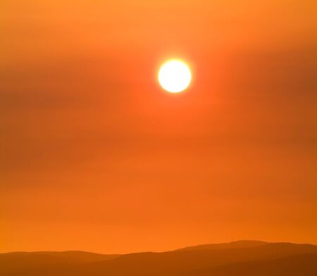 Burning orange sun shines through smoke hazeの写真素材