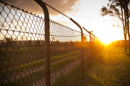 Old wire fence with the sun streaming alongside itの写真素材