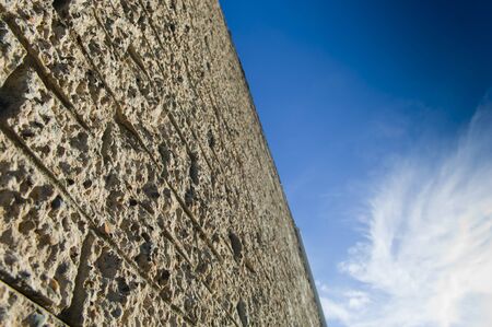Rough textured brick wall looking up to a bright blue skyの写真素材