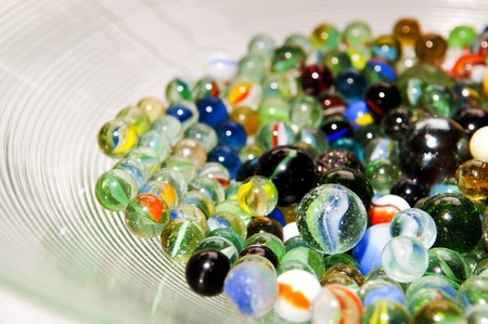 Brightly colored marbles in different shades in a bright glass bowlの写真素材