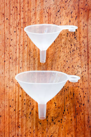 Two different sizes funnels on a wooden boardの写真素材