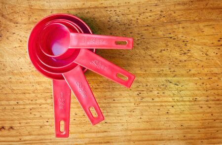 Red measuring cups in different sizes on a timber boardの写真素材