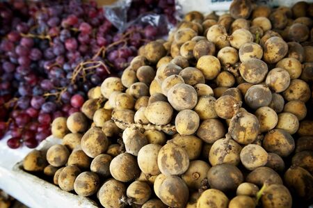 Lanzones on sale at a market with grapesの写真素材