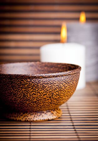 An exotic Asian style wooden bowl on bamboo with candlesの写真素材