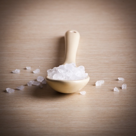 Salt in a spoon over a blured wooden background with copy spaceの写真素材
