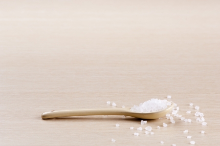 Salt in a spoon with some spilt over the wooden background with copy spaceの写真素材