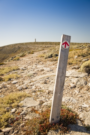 Arrow on signpost points the direction along the cliffs to the distant lighthouseの写真素材