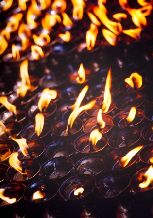 Tea light candles burning brightly in a dark room in Nepalの写真素材