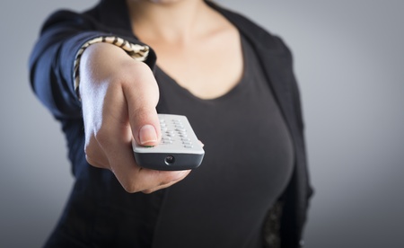 Woman holds a remote control in her hands with her body out of focusの写真素材