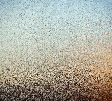 Abstract of stippled glass window pane with ambient colours from outside as background textureの写真素材