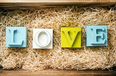 The word Love spelled out in big block letters in a wooden gift box filled with raffiaの写真素材