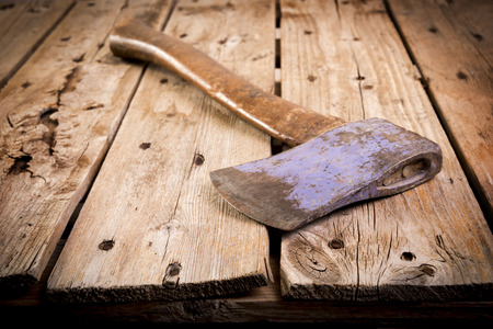 an old axe with a wooden handle and wear marks sits on a rough timberの写真素材