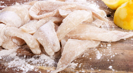 Fresh flathead fish fillets coated in flour ready for cooking with lemonsの写真素材