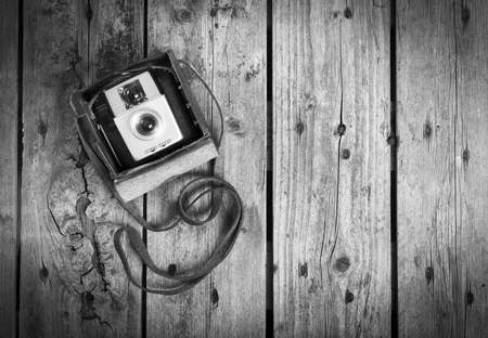 An old camera in its original vintage leather case on a wooden in black and whiteの写真素材