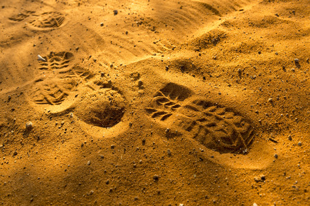 Footprints in sand at sunset in rich orange coloursの写真素材