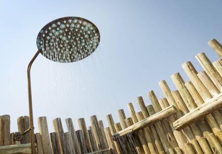 Outdoor shower with water coming out of the head and blue sky behindの写真素材