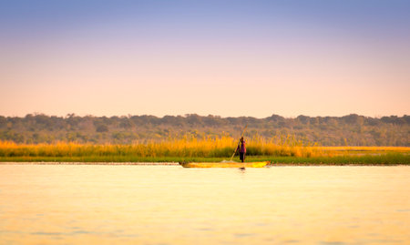KASANE, BOTSWANA - JUNE 2015 - An unidentified man paddles a wooden canoe down the Chobe River in Chobe National Park, Botswana, Africa.のeditorial素材