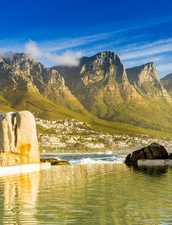 Camps Bay ocean pool at sunset with city and mountains behindの写真素材