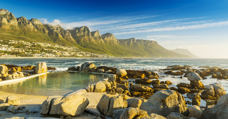 Camps Bay ocean pool at sunset with city and mountains behindの写真素材