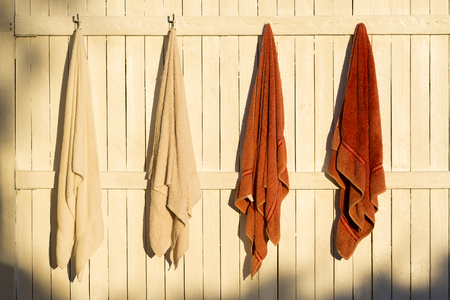 Towels hanging outdoors on hooks in the sunの写真素材