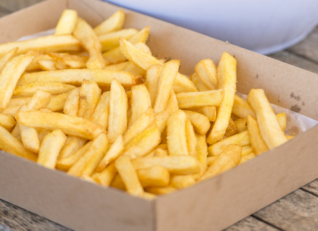 Serving of hot salty chips on a wooden tableの写真素材