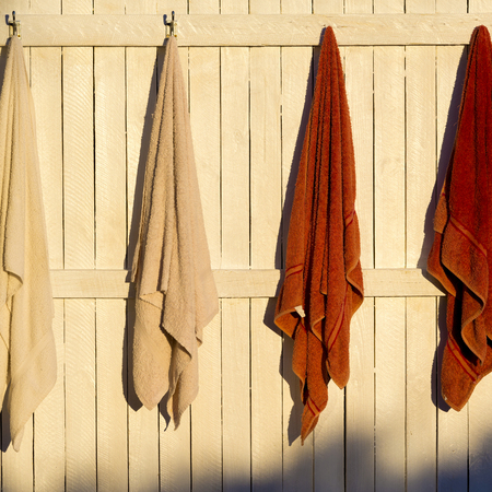 Towels hanging outdoors on hooks in the sunの写真素材