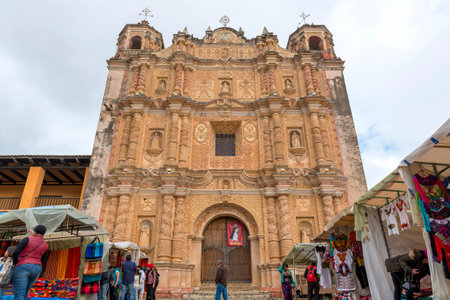 SAN CRISTOBAL, MEXICO - NOVEMBER 27: Santo Domingo Church baroque facade with unnknown people at the surrounding markets on November 27, 2016 in San Cristobal. San Cristobal de las Casas is known for its well preserved colonial architecture such as the laのeditorial素材