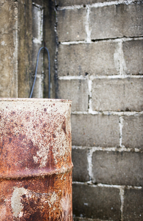 Industrial background with a rusted drum and cinder block wallの写真素材