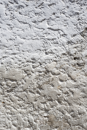 Background texture of a white stucco wall with wear and tearの写真素材
