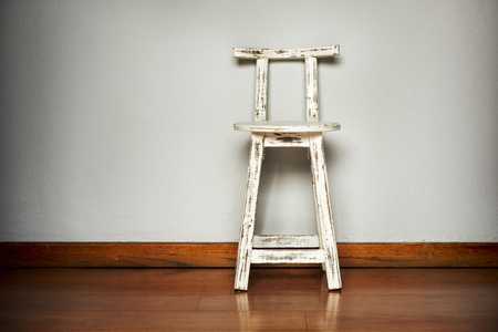 Rustic white wooden stool against a plain wall backgroundの写真素材