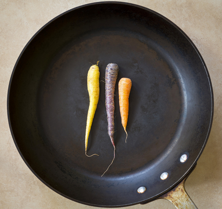 Multi colored carrots in a large black roasting panの写真素材