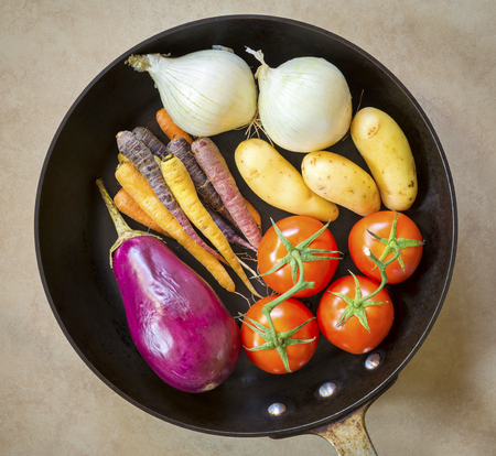 Fresh healthy vegetables ready for roasting in a deep black panの写真素材