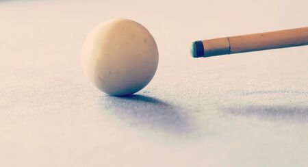 Pool cue and the white ball in shallow focus on a pool table with retro style filter effectの写真素材