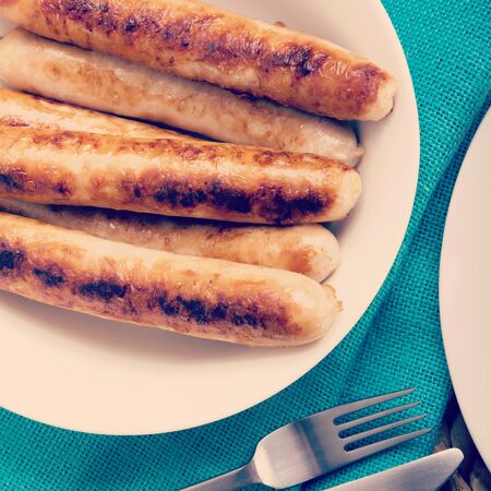 Freshly cooked chicken sausages in a white bowl with retro style filter effectの写真素材