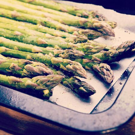 Fresh asparagus spears with salt, pepper and oil ready to be grilled or roasted with retro style filter effectの写真素材