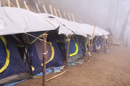 Camping tents in a row in thick cloud and fog near the summit of Acatenango volcano in Guatemalaの写真素材