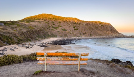 Bench at the Petrel Cove lookout with Rosetta Head or The Bluff on the Fleurieu Peninsula in South Australia at sunsetの写真素材