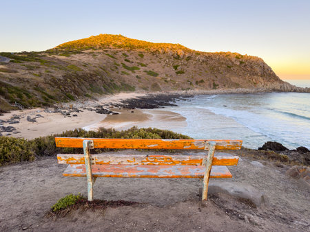 Bench at the Petrel Cove lookout with Rosetta Head or The Bluff on the Fleurieu Peninsula in South Australia at sunsetの写真素材