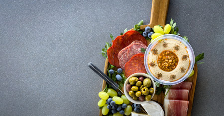 Top view of a gourmet charcuterie board or cheese platter with various meats, fruits and cheese on a...