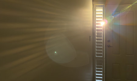 Light streams through plantation shutters on a window next to a front door as seen from the inside...