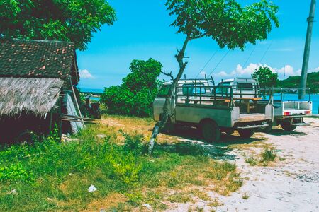 Small village in Bali with 2 cars and ocean backgroundの写真素材