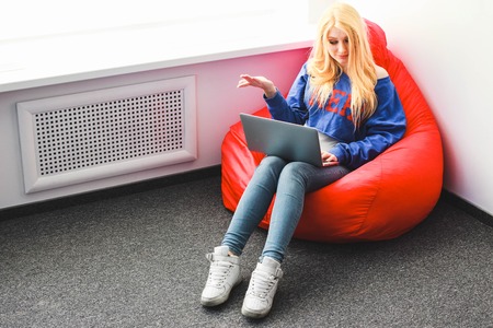 Blonde with a laptop outraged sitting on a chair-sacの写真素材