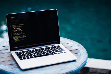 laptop on a wooden table against the background of accepted Swimming poolの写真素材