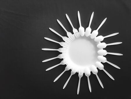 foam plate with plastic forks and plastic spoons with black backgroundの写真素材