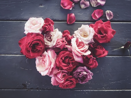 heart shape made with red and pink roses on the wooden tableの写真素材