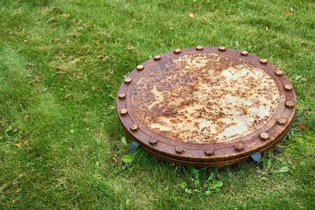 Rusty manhole on the grass