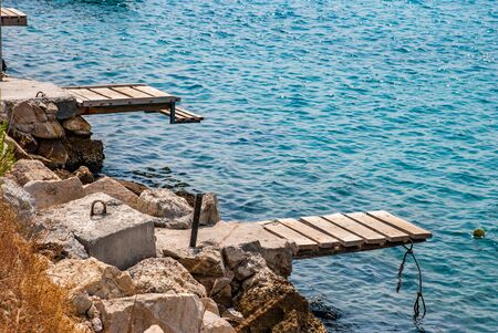 Rusty old pier near the rocky shore of the Adriatic Seaの写真素材